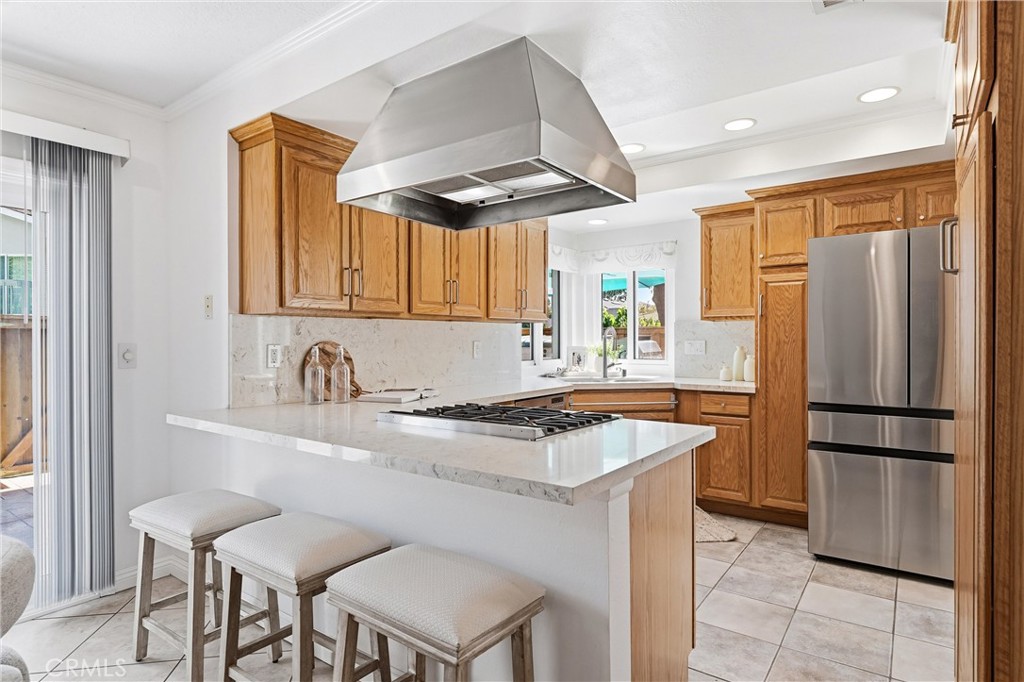 Remodeled kitchen at 8322 Padrino with quartz island, stainless hood, and bar seating